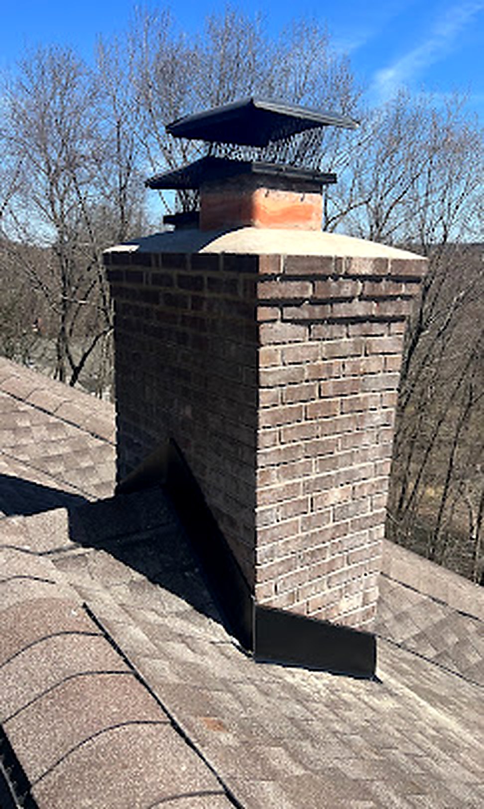 Brick chimney with double cap, woods background